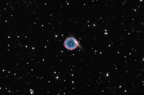 Photo of ring-shaped planetary nebula with a background galaxy