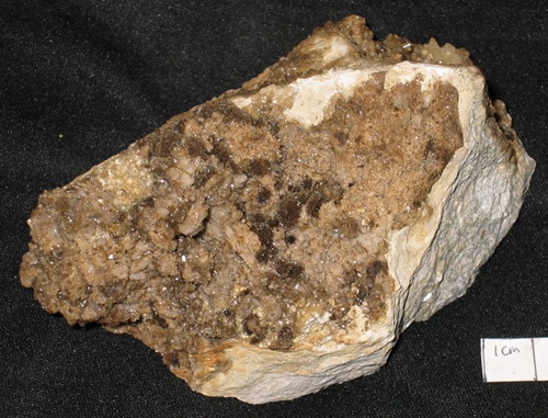 Strontianite forms dark brown balls in petroleum-stained quartz. 