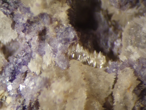 A microscope view of calcite showing parallel doubly-terminated crystals. With frothy-looking fluorite, this specimen was likely etched by acidic fluids. Collected by me November 5, 1983 from the old Austin Lead mine exposed in Hastie's Quarry in 1986. View ~1 cm.