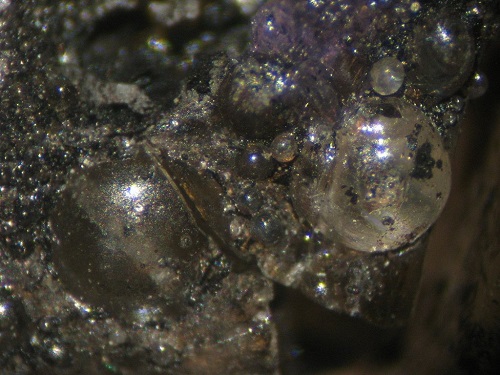Photo Hy2, Bitumen (dried hydrocarbons) around calcite spheres (and fluorite spheres above), from the Hastie's property, collected in 1984. FOV ~ 5mm.